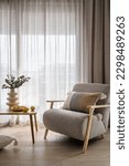 Small photo of Plants in vase and plate with yellow citrus lemons on wooden table close to comfy soft chair with decorative cushion. Grey armchair perfect addition to light and airy living room in urban apartment