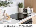 bottles of household chemicals in metal basket on countertop and wooden brushes for cleaning electrical glass ceramic stove and other appliances at kitchen