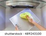 Woman Cleaning Cooker Hood With Rag In Kitchen At Home