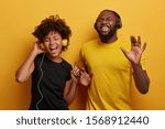 Small photo of Happy girlfrind and boyfriend sing song and dance with rhythm of music, listen favourite songs in headset, enjoy new track, wear casual clothes, isolated over yellow wall. Lets have fun together