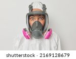 Small photo of Ecological disaster and chemical pollution concept. Shocked woman dressed in protective suit and gas mask tries to liquidate agent and save planet isolated over white studio background. Save planet