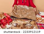 Cropped shot of faceless baker holds tray with cut raw gingerbread cookies before baking stands near messy table with ingredients enjoys xmas culinary gives biscuit recipe. Christmas preparations