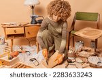 Small photo of Indoor shot of busy female jointer assembles wooden chair has concentrated look works in workshop long hours uss variety of tools dressed in jumper and overalls. Skilled young woman carpenter
