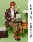 Small photo of Annoyed redhead female office worker screams angrily holds handset works on typewriter has quarrel with someone on distance poses on chair sits near old table uses typing machine. Retro woman typist