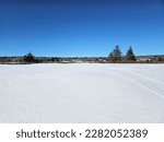 Small photo of A wide shot of a large unplowed parking lot that is snow covered.