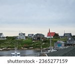 Small photo of Peggy's Cove, NS, CAN, August 15, 2023 - A view of the houses on a hill along the water at Peggy's Cove, Nova Scotia on a cloudy morning.