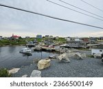 Small photo of Peggy's Cove, NS, CAN, August 15, 2023 - A view of the houses on a hill along the water at Peggy's Cove, Nova Scotia with vessels docked in the water.