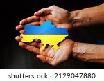 Support for Ukraine in the war with Russia. Hands holding the flag of Ukraine in the shape of the borders of Ukraine.