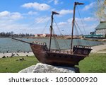 Small photo of Slavyansk-on-Kuban, Russia - March 19, 2018: Wooden boat with masts for sails. The model of the ship in front of the lake in the city of Slavic-on-Kuban. An uneventful author, a public monument.