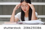 Small photo of Asian student women read books in library at university. Young undergraduate girl stress tired have problem while study hard for knowledge on lecture desk at college campus concept.