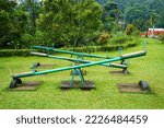 Small photo of A seesaw (teeter-totter or teeterboard) is a long, narrow board supported by a single pivot point, the midpoint between both ends; as one end goes up, the other goes down. Found at parks and school.