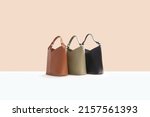 Beautiful brown, green, black leather female fashion bag isolated on light beige background, perspective view