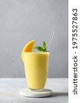 Small photo of Indian ayurvedic mango lassie or lassi on light gray background. Vertical format. Traditional healthy drink with mango. Freshness lassi made of yogurt, water, spices, fruits and ice.
