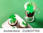 Irish coffee and special cupcakes for Happy St Patricks Day on green background. Close up. Copy space. Festive traditional food.