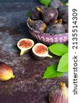 Small photo of fresh ripe figs on dark table. Healthy Mediterranean fig fruit. Fresh figs on a dark background. Beautiful blue violet figs with leaves, copy space
