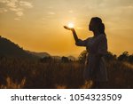 Silhouette of  beautiful young woman in barley field white sun on hand.