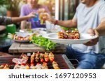 A man with a barbecue plate at a party between friends. Food, people and family time concept.