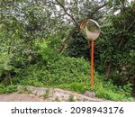 Small photo of Round convex traffic mirror on the alley for better visibility. Convex mirrors provide a wider field of view on roads, driveways and in alleys.