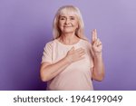 Small photo of Aged woman hand on heart make oath sign isolated over violet background