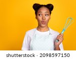Small photo of Photo of young lovely african woman plump lips curious look empty space hold whisk cook supper isolated over yellow color background