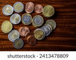 Small photo of Argentine coins of different values on a wooden background. In disuse due to uncontrolled monetary emission. Inflation.