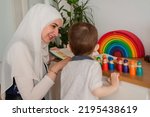 Small photo of A Musllim teacher and preschool child playing together with colorful toys in the Montessori school classroom or kindergarten.