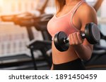 Workout in gym by a beautiful Asian woman , woman is using dumbbell . Sport woman warm up before workout .
