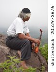 Small photo of The old asceted with his interludes sat on a rock. Mount Arjuna. Pasuruan, Indonesia, October 5, 2021