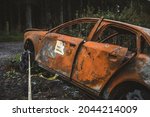 Stolen car burned out and abandoned marked as a crime scene with police tape