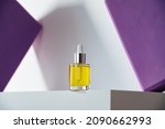 face oil in glass bottle with dropper on white podium and geometric purple background. Modern self-care minimalism in cosmetics and skin-care. Hero shot