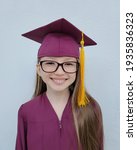 Small photo of Smiling Causation girl with glasses in a graduation gown and hat. White background. Graduation