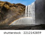 Low angle view of the mighty Skógafoss waterfall under a clear blue sky, with a beautiful double rainbow caused by its constant spray, near Route 1, Ring Road, Southern Region, Iceland