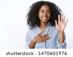Small photo of Girl makes promise. Portrait friendly-looking sincere cute african-american woman telling truth raise one hand put arm heart pledging, giving oath smiling swear, standing white background