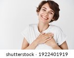 Close up of happy smiling woman say thank you, holding hands on heart grateful, express gratitude, standing against white background.