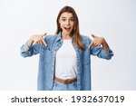 Wow look there. Excited blond young woman pointing fingers down with surprised face, showing awesome promo, demonstrating advertisement, white background