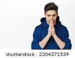 Small photo of Close up portrait of calm man praying, clasp hands together and making wish, pleading, standing over white background