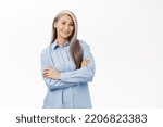 Small photo of Smiling beautiful senior korean woman, looking self-assured and confident, concept of wellness and people wellbeing, standing over white background.