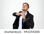 Small photo of Young successful businessman taking tie off over white background.