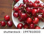 Fresh red cherries fruit on plate on wooden background close up. High quality photo