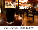 Small photo of Pint glass of typical Irish stout on table in a pub