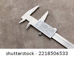 Opened jaws metal vernier caliper with measurement conversion table on the rusty grunge background