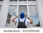 Experienced worker holds mosquito net in his hands, professionally installs it on window outside building. Professional installation of protective nets against insects on plastic windows of any size
