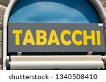 Small photo of Rome, Italy - August 9, 2018: Signage Tabacchi, Italian for Tobacco shop, on a black background. Also called a tobacco shop, a tobacconist's shop or a smoke shop, it is a retailer of tobacco products