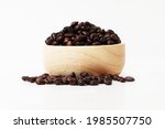  small  wooden cup with coffee beans inside overflowing from the cup on white background.