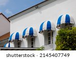 Small photo of blue and white striped curve awning above the window at balconay of house. Sunshade for store.