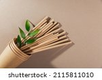 Small photo of Catering and street fast food paper cups, straws and green leaves. Accessories for eating and drinking outdoors. Ecology, recycling concept.