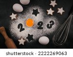 Creative Happy New Year 2023 greeting card for home baker. Numbers made out of flour with egg yolk, Christmas baking concept, top view
