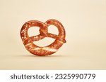 Small photo of Appetizing traditional Bavarian pretzel baked bun isolated on the bright solid fond plain yellow background