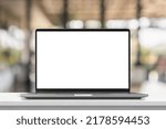 Laptop with blank screen on marble table with cafe coffee shop blur background