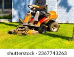 Small photo of gardener mows the lawn on a lawn mower. lawn mower cuts the grass on the lawn.